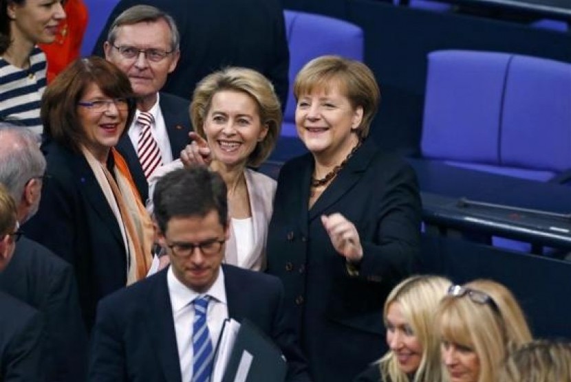 Designated Defence Minister Ursula von der Leyen (center), gestures as she stands beside German Chancellor Angela Merkel (right), during a meeting of the Bundestag, the lower house of parliament, to elect the German Chancellor, in Berlin December 17, 2013.