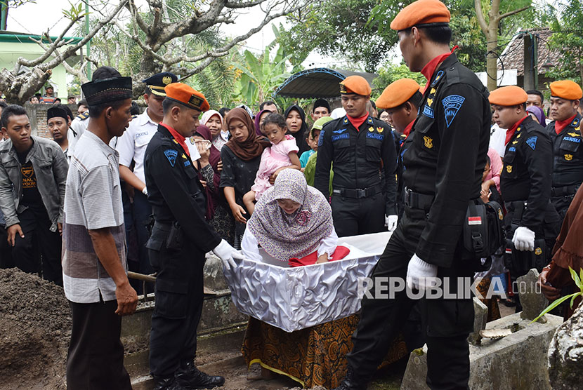 Dian Kartika Utami Sari (tengah), isteri Mustofa masinis Kereta Api (KA) Sancaka yang tewas kecelakaan, melihat jenazah suaminya untuk terakhir kali sebelum dimakamkan di Desa Sumberbening, Balerejo, Kabupaten Madiun, Jawa Timur, Sabtu (7/4). 