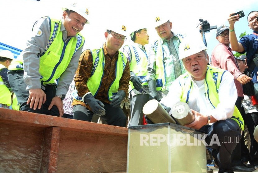 Bersama para pejabat lainnya, Menteri PUPR Basuki Hadimujono mencoba beton teknologi Mortar Busa yang mengambang di air pada Ground Breaking Fly Over atau Jembatan Layang Antapani, Kota Bandung, Jumat (10/6). (Republika/Edi Yusuf)