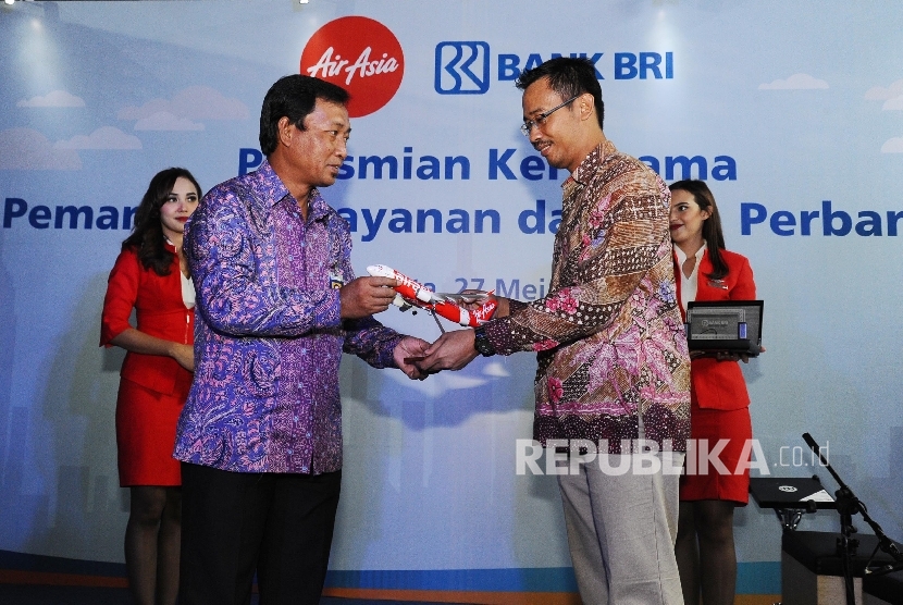 Direktur Bank BRI Sis Apik Wijayanto (kiri), Presiden Direktur AirAsia Indonesia Sunu Widyatmoko (kanan) saat melakukan penukaran cinderamata usai penandatanganan kerjasama di Jakarta, Jumat (27/5).(Republika/Tahta Aidilla)