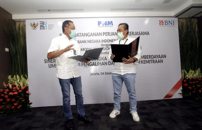 Direktur Bisnis UMKM BNI Muhammad Iqbal (kiri) dan Direktur Kepatuhan dan Manajemen Risiko PNM M. Q. Gunadi (kanan) menandatangani PKS tentang Sinergi BUMN Dalam Rangka Peningkatan Pemberdayaan UMKM Melalui Pengalihan Dana Program Kemitraan di Jakarta, Jumat (4 Desember 2020). Hingga saat ini, sudah lebih dari 10.000 debitur yang menerima manfaat penyaluran kredit hasil kerjasama antara BNI dan PNM.