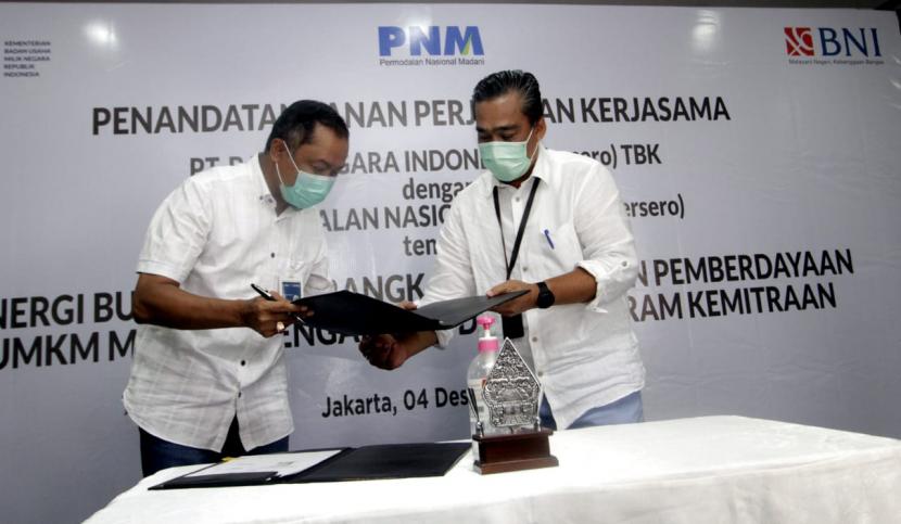 Direktur Bisnis UMKM BNI Muhammad Iqbal (kiri) dan Direktur Kepatuhan dan Manajemen Risiko PNM M. Q. Gunadi (kanan) menandatangani PKS tentang Sinergi BUMN Dalam Rangka Peningkatan Pemberdayaan UMKM Melalui Pengalihan Dana Program Kemitraan di Jakarta, Jumat (4 Desember 2020). Hingga saat ini, sudah lebih dari 10.000 debitur yang menerima manfaat penyaluran kredit hasil kerjasama antara BNI dan PNM.