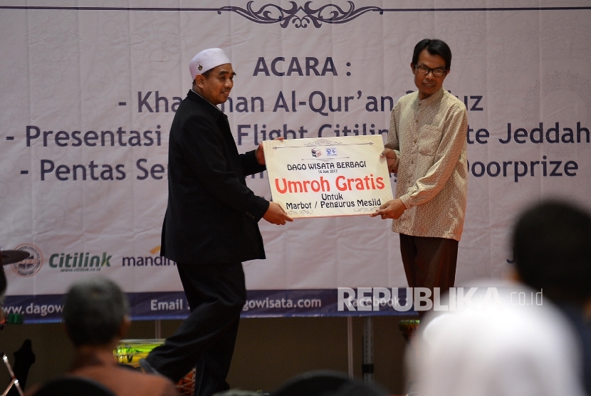 Direktur Dago Wisata Dodi Sudrajat (kiri) menyerahkan paket umrah gratis kepada marbo (pengurus mesjid) saat acara Dago Wisata Berbagi di Ballroom Grandia Hotel, Jalan Cihampelas, Kota Bandung, Jumat (16/6).