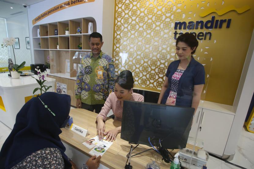 Direktur Finance, Risk & Operation Bank Mandiri Taspen Atta Alva Wanggai (kiri) bersama Kepala Cabang Pembantu Thamrin Bank Mandiri Taspen Diana Susanti (kanan)  sedang memperhatikan petugas teller menjelaskan produk dan layanan finansial Bank Mandiri Taspen kepada nasabah, seusai peresmian Kantor Cabang Pembantu (KCP) Jakarta Thamrin, di Wisma Mandiri, Jakarta, Kamis (10/11).