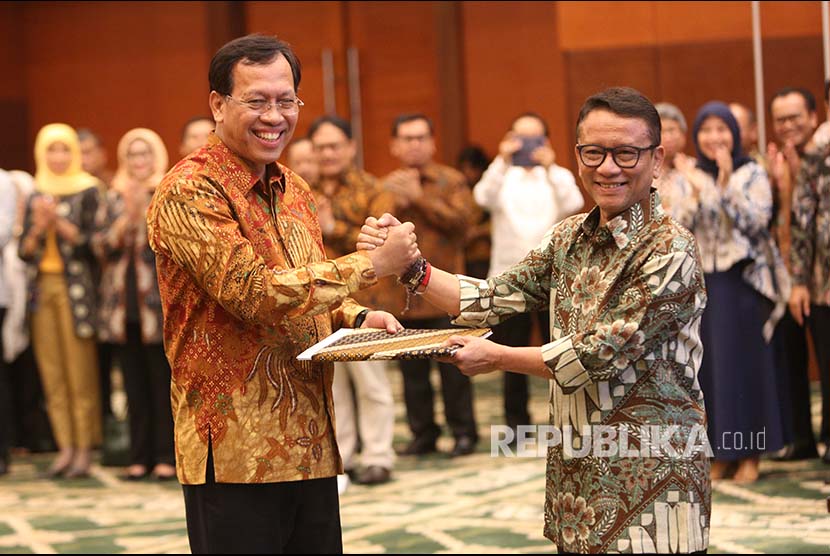 Direktur Jenderal Pajak Kementerian Keuangan yang baru  Robert Pakpahan (kiri) berjabat tangan dengan pejabat lama Ken Dwijugiasteadi saat serah terima jabatan di kantor Kementerian Keuangan (Kemenkeu), Jakarta, Kamis (30/11). 