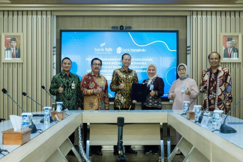 Direktur Komersial dan UMKM Bank BJB Nancy Adistyasari (ketiga kanan) dan Direktur Utama Bank Bengkulu Ahmad Irfan (ketiga kiri) menunjukkan nota perjanjian kerja sama (PKS) kelompok usaha bank (KUB) di Menara Bank BJB, lantai 7, Jalan Naripan, Kota Bandung, Jumat (29/7).   