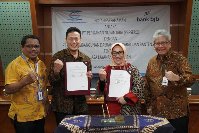 Direktur Konsumer dan Ritel bank bjb Suartini (kedua kanan) dan Direktur Keuangan, SDM dan Umum Perinus Henda Tri Retnadi (kedua kiri) menunjukkan MoU terkait kerja sama permodalan nelayan di Menara Bank BJB, Kota Bandung, Jumat (11/10). Penandatanganan MoU disaksikan oleh Direktur Operasional dan Pemasaran Perinus J Ronald Abraham Tanamal (kiri) dan Dirut Bank BJB Yuddy Renaldi (kanan).