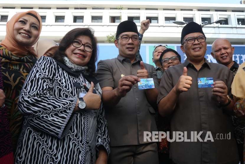 Direktur Operasional Bank BJB Fermiyanti (kedua kiri) bersama Wali Kota Bandung Ridwan Kamil (tengah) dan Wakil Wali Kota Bandung Oded M Danial memperlihatkan Bandung Smart Card (BSC) usai penandatanganan perjanjian kerjasama antara Pemerintah Kota Bandung dengan delapan perbankan nasional, mengenai penerbitan kartu multifungsi BSC, di Balai Kota Bandung, Senin (13/8).