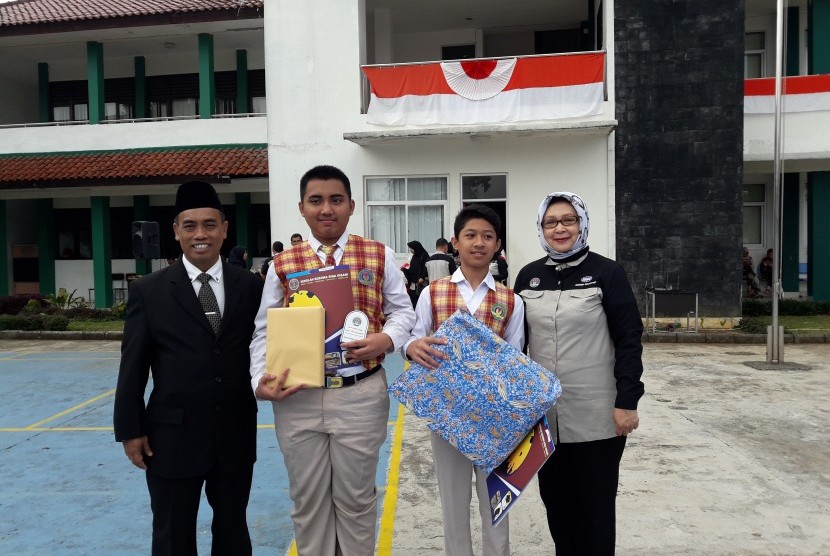 Direktur Pendidikan Sekolah Bosowa Bina Insani (SBBI) Sudirman (kiri) dan Kepala Hubungan Kelembagaan & PR SBBI Dedeh Soeria Atmadja (kanan) bersama dua siswa berprestasi.