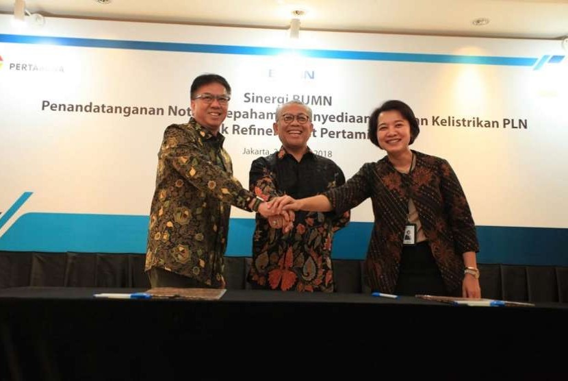 Direktur Pengolahan Pertamina Budi Santoso Syarif (kiri) berpegangan tangan dengan Direktur Perencanaan Korporat PLN Syofvi Felienty Roekman (kanan) usai penandatanganan nota kesepahaman kerja sama di Jakarta, Jumat (3/8).