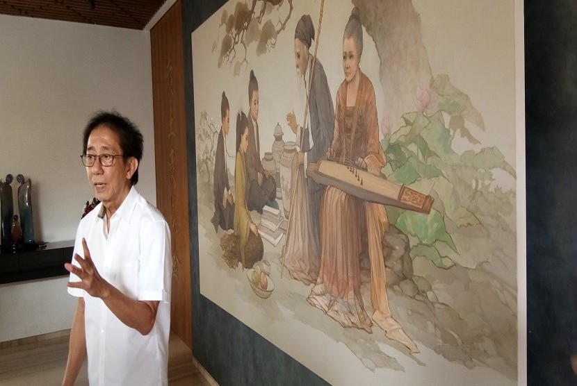 Direktur PT Sido Muncul Irwan Hidayat dengan latar belakang lukisan yang memuat filosofi kerukunan keluarga.
