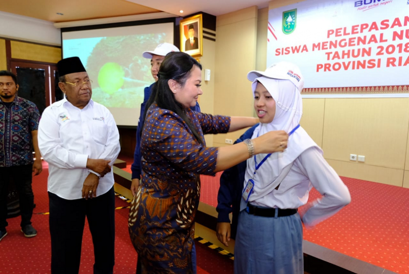 Direktur SDM dan Umum PT PGN Tbk Desima E. Siahaan memakaikan name tag dan topi ke perwakilan siswa peserta SMN sebagai simbolisasi pelepasan para siswa asal Riau ke Maluku, Senin (13/8).