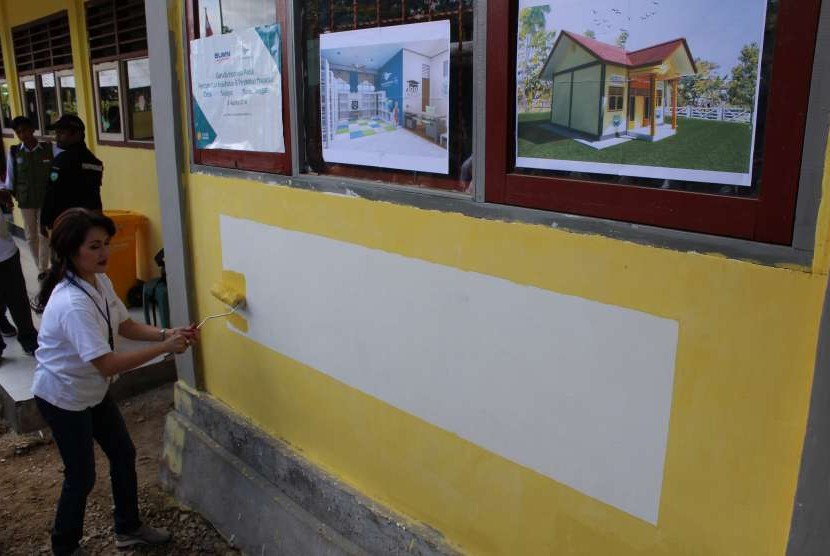 Direktur SDM & Umum Garuda Indonesia, Linggarsari Suharso mengecat dinding  Taman Bacaan Masyarakat Desa Selayar, Tual, Maluku Tenggara, Jumat (3/8).