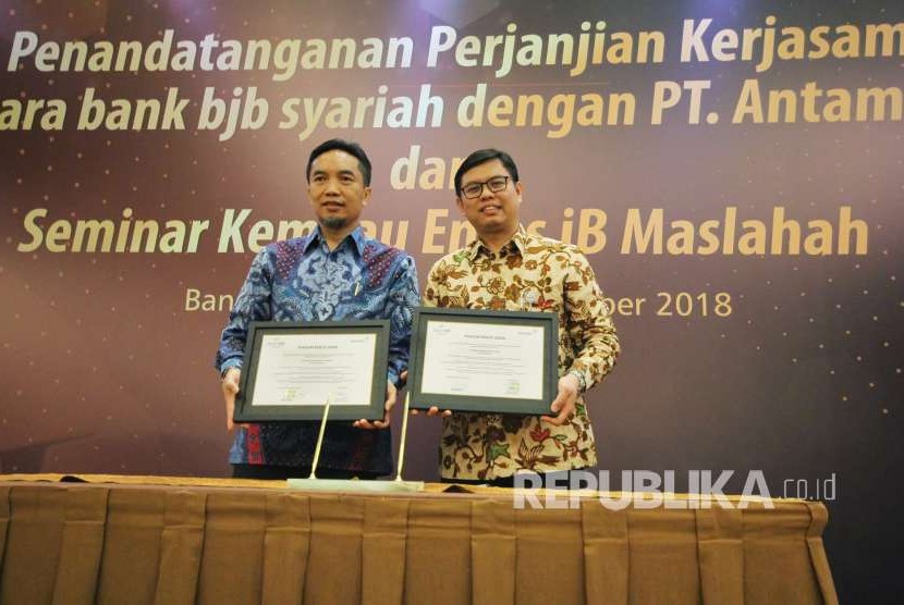 Direktur Utama Bank BJB Syariah Indra Falatehan (kanan) dan Direktur Pemasaran PT Antam TBK Tatang Hendra memperlihatkan Piagam Kerjasama usai penandatanganan kerjasama antara Bank BJB Syariah dan PT Antam di Hotel Prama Grand Preanger Bandung, Kota Bandung, Jumat (14/9).