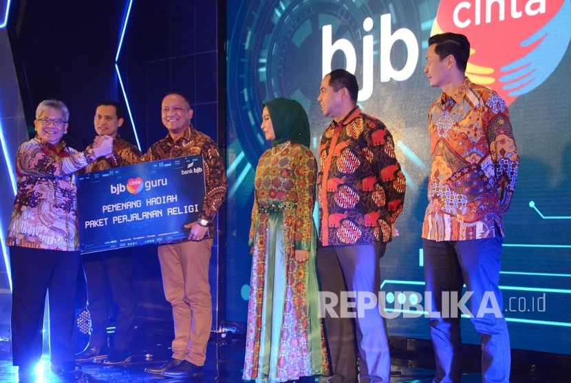 Direktur Utama Bank BJB Yuddy Renaldi (kiri) menyerahkan hadiah Paket Perjalanan Religi program BJB Cinta Guru kepada perwakilan guru, di Kota Bandung, Jumat (14/2).