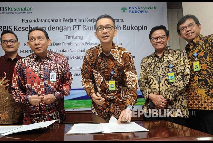 Direktur Utama Bank Syariah Bukopin Saidi Mulia Lubis (tengah), menandatangani naskah kerja sama bersama Direktur Keuangan dan Investasi BPJS Kesehatan Kemal Imam Santoso (kedua kiri), di Jakarta, Kamis (20/9). 