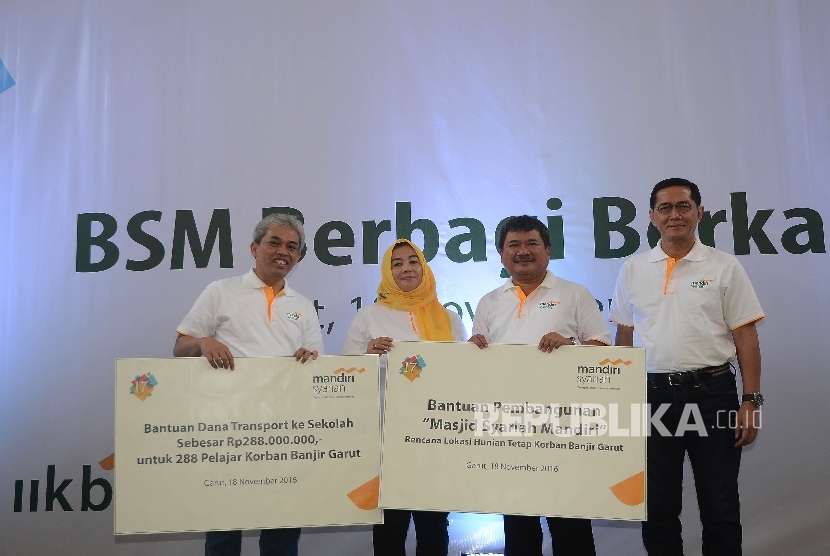 Direktur Utama Bank Syariah Mandiri (BSM) Agus Sudiarto (kiri) dan Komisaris Utama BSM Ventje Rahardjo (kanan) foto bersamam usai simbolis menyerahkan bantuan kepada Bupati Garut Rudi Gunawandi (kedua kanan) untuk korban banjir bandang pada acara 17 tahun 