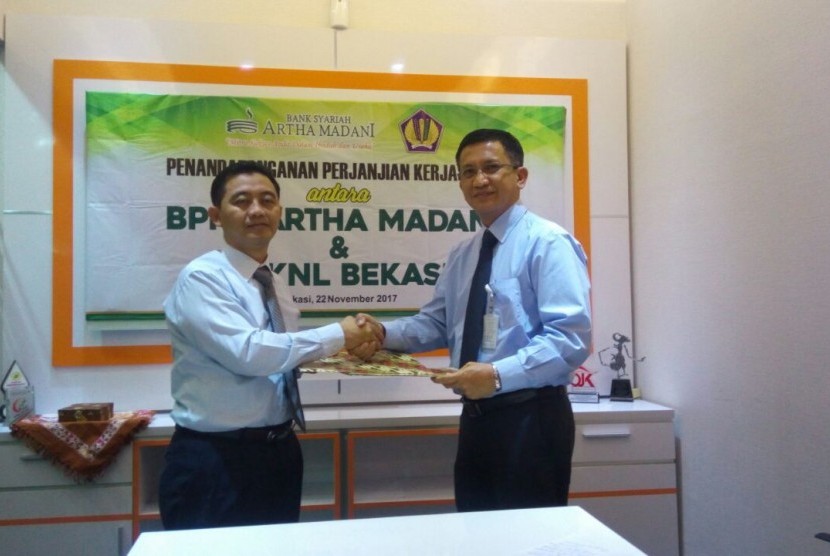 Direktur Utama BPRS Artha Madani Cahyo Kartiko (Kiri) berjabat tangan dengan Kepala Kantor KPKNL Partolo usai menandatangani kesepakatan kerja sama lelang di kantor pusat BPRS Artha Madani Kota Bekasi, Jawa Barat