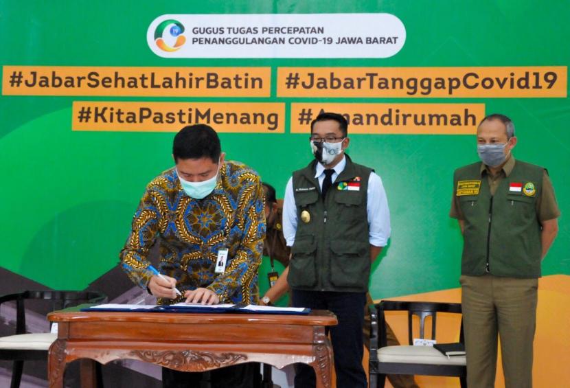 Direktur Utama PT Pegadaian (Persero) Kuswiyoto (kiri) dan Gubernur Jabar Ridwan Kamil (tengah) menandatangani kerja sama penanggulangan warga terdapak Covid-19 di Gedung Pakuan, Kota Bandung (4/5). Kerja sama tersebut melibatkan juga Perum Bulog dan PT Pos.