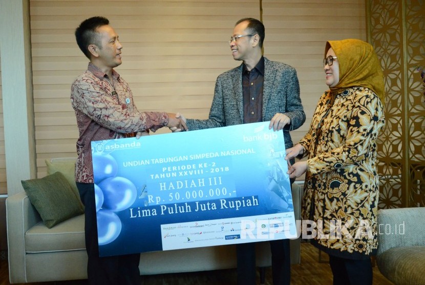 Dirut Bank BJB Ahmad Irfan (kedua kanan) di dampingi Direktur Retail & Konsumer Bank BJb Suartini (kanan) secara simbolis menyerahkan hadiah undian Simpeda Periode Ke-2 Tahun 2018 kepada pemenang ketiga Enang, di Kantor Bank BJB, Jalan Naripan, Kota Bandung, Kamis (12/4). 