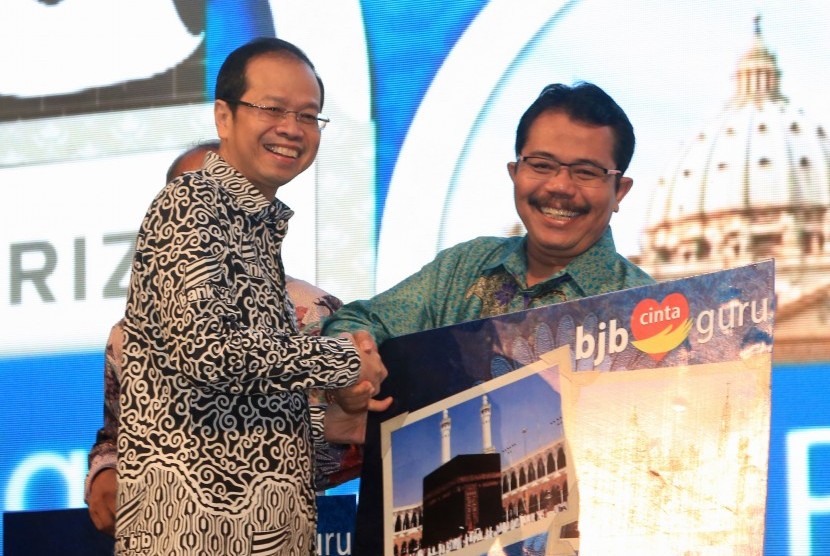 Dirut Bank BJB Ahmad Irfan (kiri) menyerahkan secara simbolik grandprize berupa wisata religi dalam ajang penarikan Undian BJB Cinta Guru di Intercontinental Hotel, Dago Resort Bandung, Rabu (1/2) malam. 