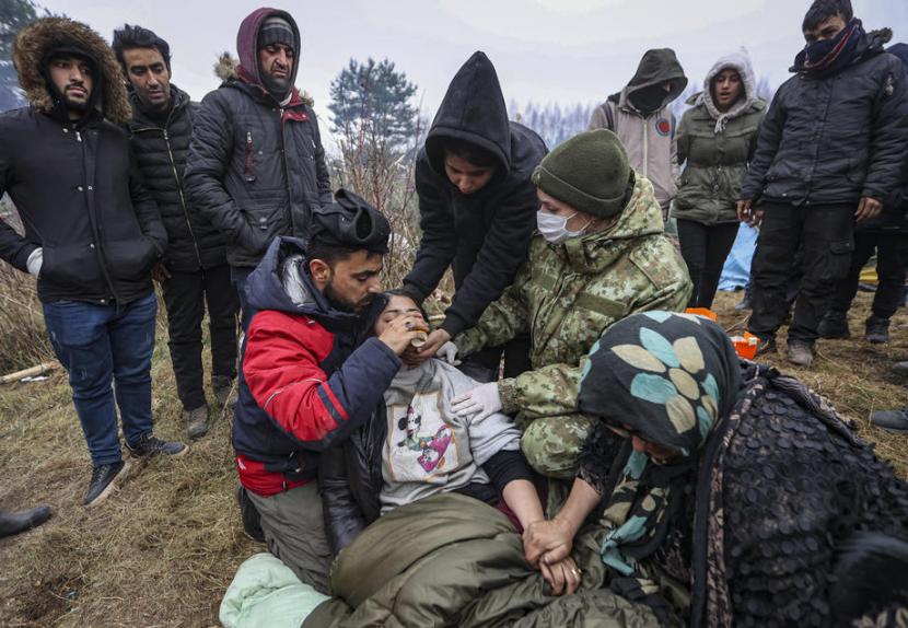 Dokter militer Belarusia memberi perawatan medis kepada seorang imigran di perbatasan Belarusia-Polandia, 11 November 2021. Pengungsi bertaruh nyawa demi ke Eropa menghadapi kejahatan dan keganasan alam.