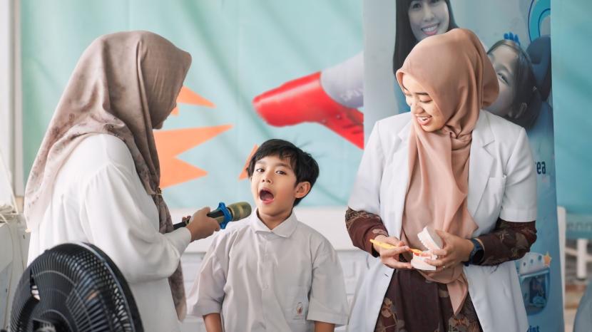Dokter sedang memeriksa gigi siswa.