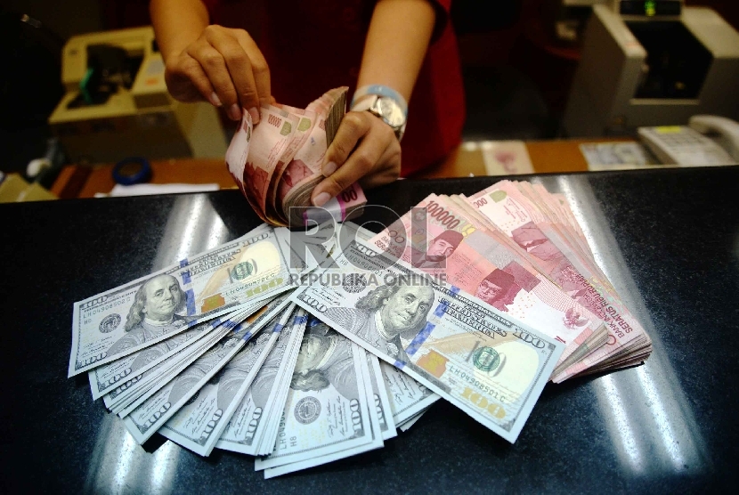 Dollar Naik, Rupiah Turun: Petugas menghitung uang pecahan 100 Dollar dan uang pecahan Rp. 100 ribudi salah satu tempat penukaran uang, Jakarta, Kamis (12/2).