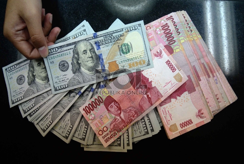 Dollar Naik, Rupiah Turun: Petugas menghitung uang pecahan 100 Dollar dan uang pecahan Rp. 100 ribudi salah satu tempat penukaran uang, Jakarta, Kamis (12/2).