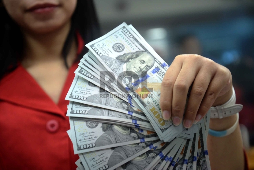 Dollar Naik, Rupiah Turun: Petugas menghitung uang pecahan 100 Dollar dan uang pecahan Rp. 100 ribu di salah satu tempat penukaran uang, Jakarta, Kamis (12/2).