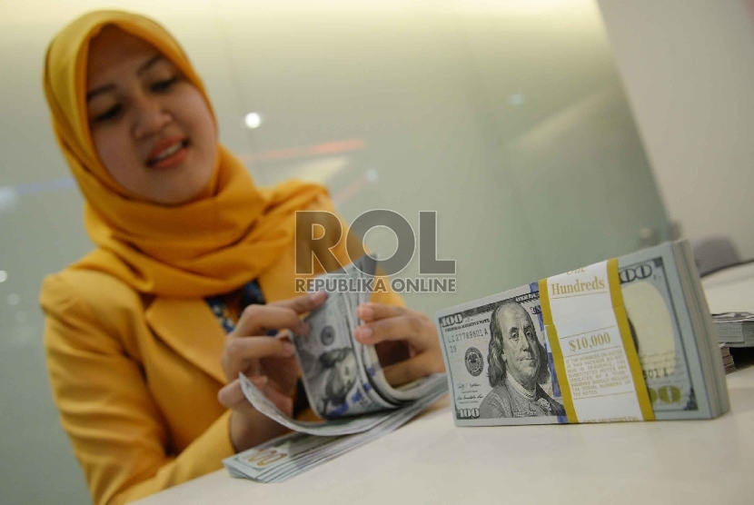 Dollar Semakin Menguat: Teller menghitung dollar di Banking Hall Bank Mandiri, Jakarta, Rabu (11/3).