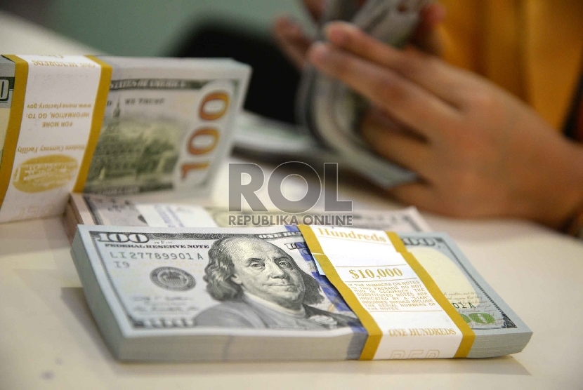 Dollar Semakin Menguat: Teller menghitung dollar di Banking Hall Bank Mandiri, Jakarta, Rabu (11/3).