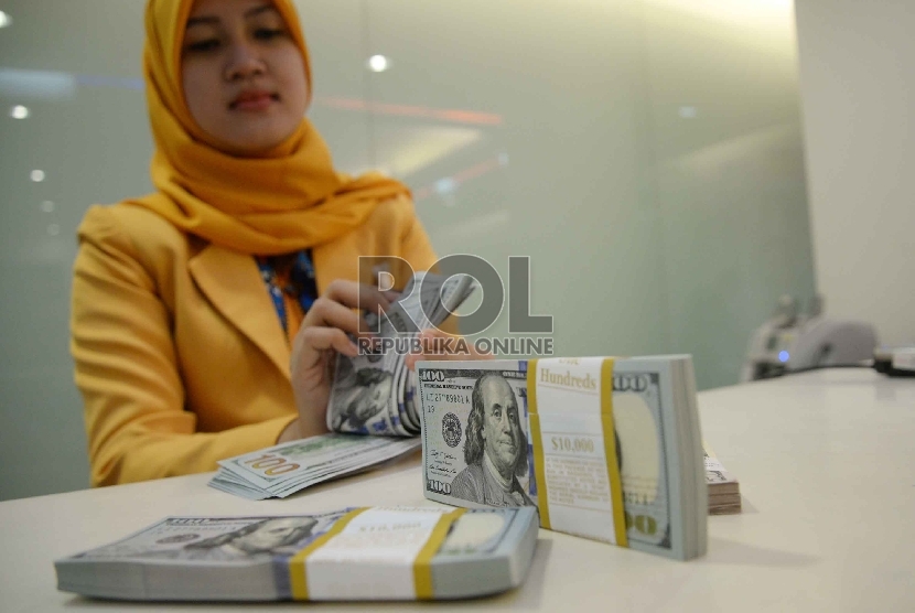 Dollar Semakin Menguat: Teller menghitung dollar di Banking Hall Bank Mandiri, Jakarta, Rabu (11/3).