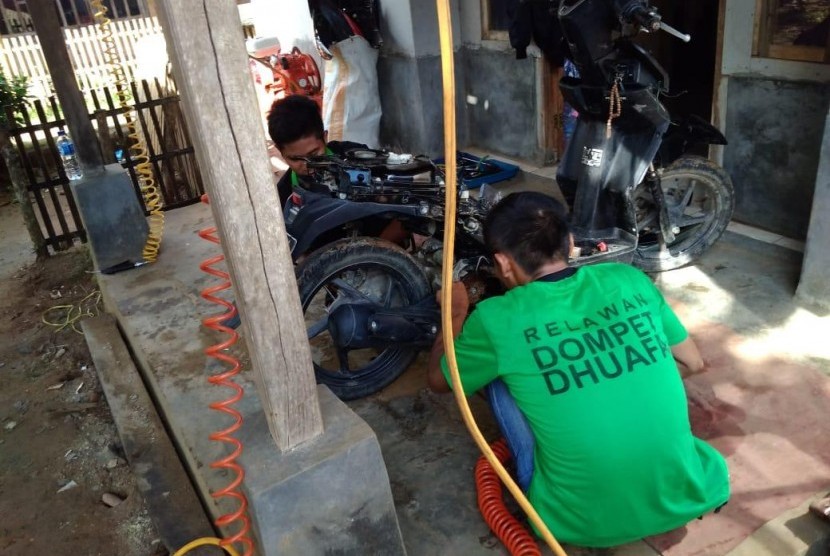 Dompet Dhuafa Beri Servis Sepeda Motor Gratis untuk Korban Tsunami. Tampak tim Dompet Dhuafa sedang memperbaiki sepeda motor warga Kecamatan Sumur, Pandeglang, Banten, Ahad (30/12). 