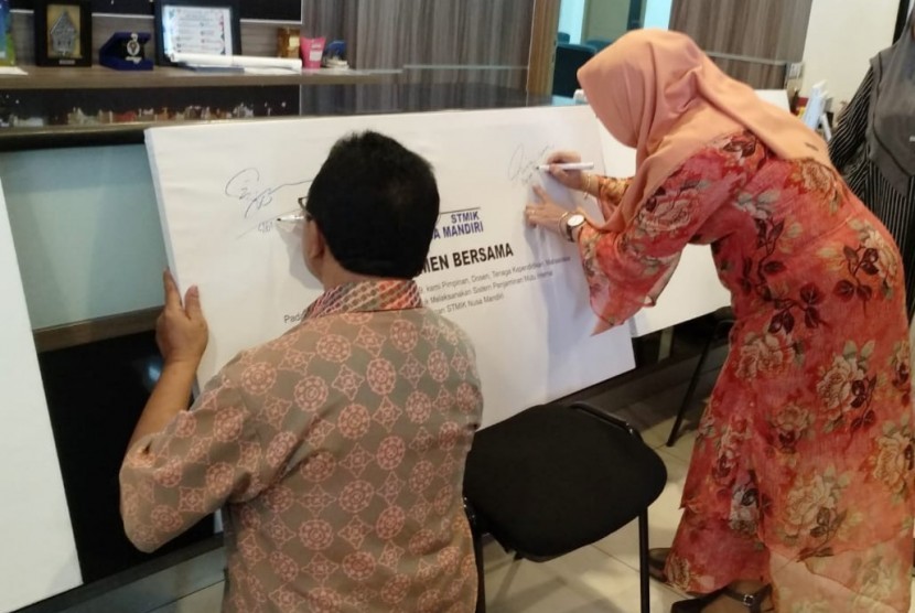 Dr Dwiza Riana dan Sigit Swasono saat menandatangani simbolis komitmen bersama seluruh civitas akademik STMIK Nusa Mandiri untuk melaksanakan Sistem Penjamin Mutu Internal (SPMI).