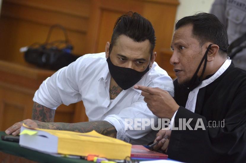 Drummer Superman is Dead I Gede Ari Astina alias Jerinx (kiri) berbincang dengan kuasa hukumnya I Wayan Gendo Suardana (kanan) saat sidang di Pengadilan Negeri Denpasar, Bali
