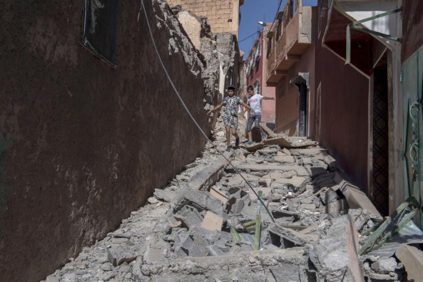 Dua anak berjalan di puing-puing reruntuhan akibat gempa di Marrakesh, Maroko, Sabtu (9/9/2023). Setidaknya 800 orang dilaporkan meninggal dan 600 orang terluka. Gempa Jumat (8/9/2023) tersebut bermagnitude 6,8. 