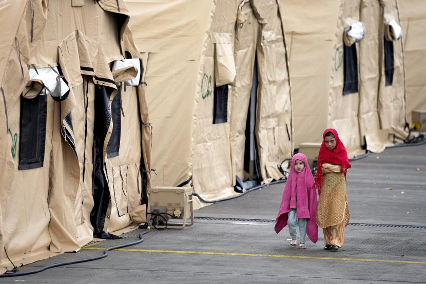 Dua anak berjalan di samping tenda di Pangkalan Udara AS Ramstein di Ramstein, Jerman, Senin, 30 Agustus 2021. Komunitas militer Amerika terbesar di luar negeri menampung ribuan pengungsi Afghanistan di kota tenda di pangkalan udara.