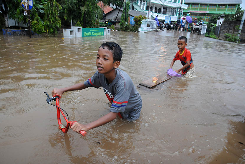 Dua anak bermain di depan pemukiman mereka yang terendam banjir di Perumahan Bukit Cengkeh II, Cimanggis, Depok, Jawa Barat, Jum'at (12/2).  (Antara/Indrianto Eko Suwarso)