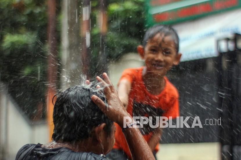 Dua anak bermain saat hujan di Depok, Jawa Barat, Sabtu (27/11/2021). 