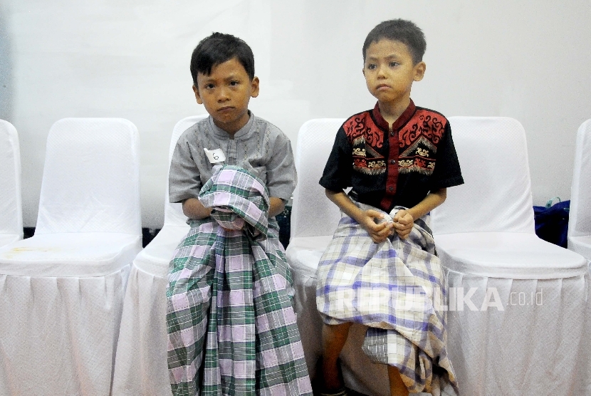  Dua anak duduk didekat tempat khitanan massal seusai di khitan yang diselenggaran dalam HUT ke-56 Bank BJB di Jakarta, Ahad (14/5). 