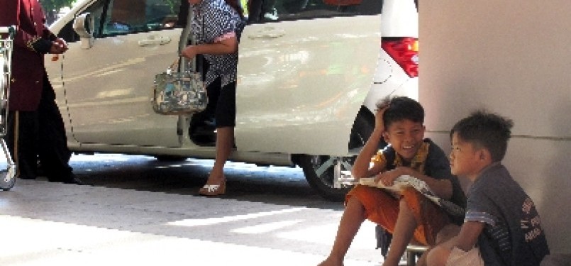 Dua anak jalanan penjual koran, duduk di emperan pintu masuk salah satu mal di Surabaya. Anak jalanan rawan jadi korban human trafficking.