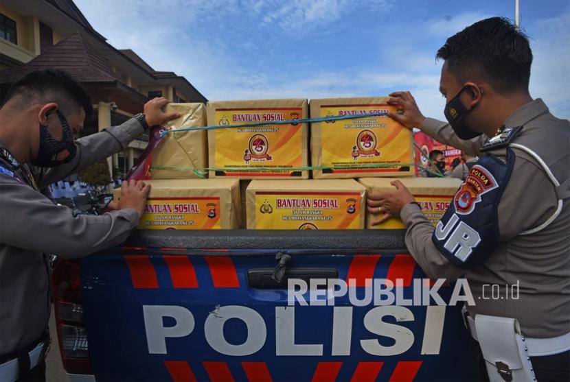 Dua anggota polisi menyiapkan paket bantuan sembako untuk warga terdampak pandemi. 