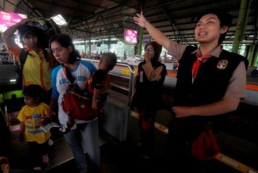 Dua anggota Pramuka memberikan arahan kepada pemudik Kereta Api di Stasiun Gambir, Jakarta, Senin (5/8).