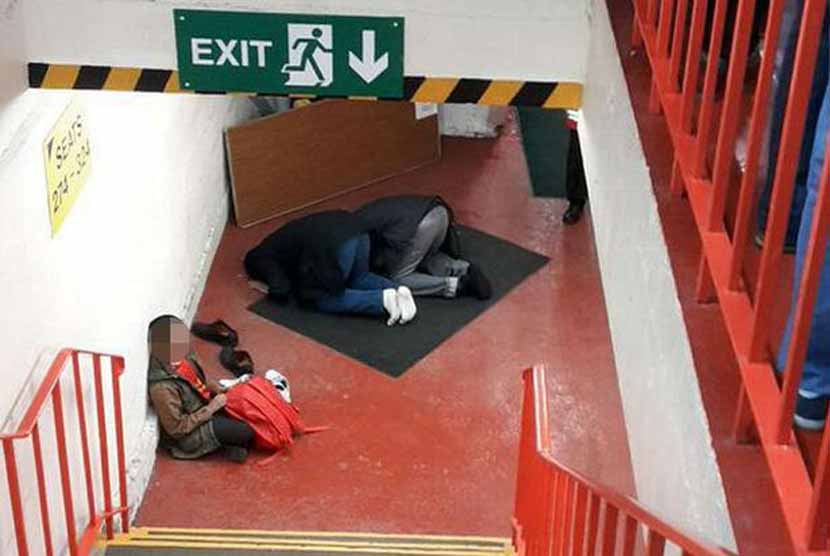 Dua fans Liverpool shalat di lorong tangga Stadion Anfield. 