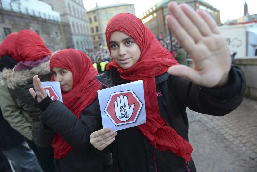 Dua gadis muda membawa selembaran 'jangan sentuh masjidku' sebagai bentuk protes terhadap aksi pelecehan terhadap masjid-masjid di Stockholm, Swedia, pada 2 Januari 2015. 