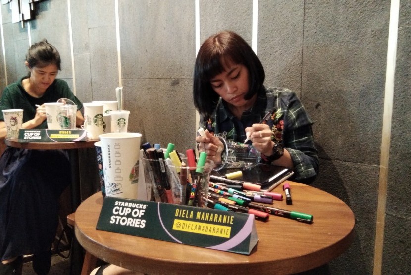 Dua ilustrator sedang menggambar dengan kanvas gelas Starbucks di peluncuran kampanye Starbucks Cup of Stories di Senayan, Jakarta.