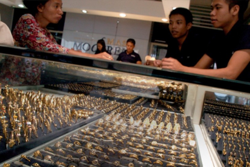 Dua karyawan melayani calon pembeli perhiasan emas di salah satu toko emas.