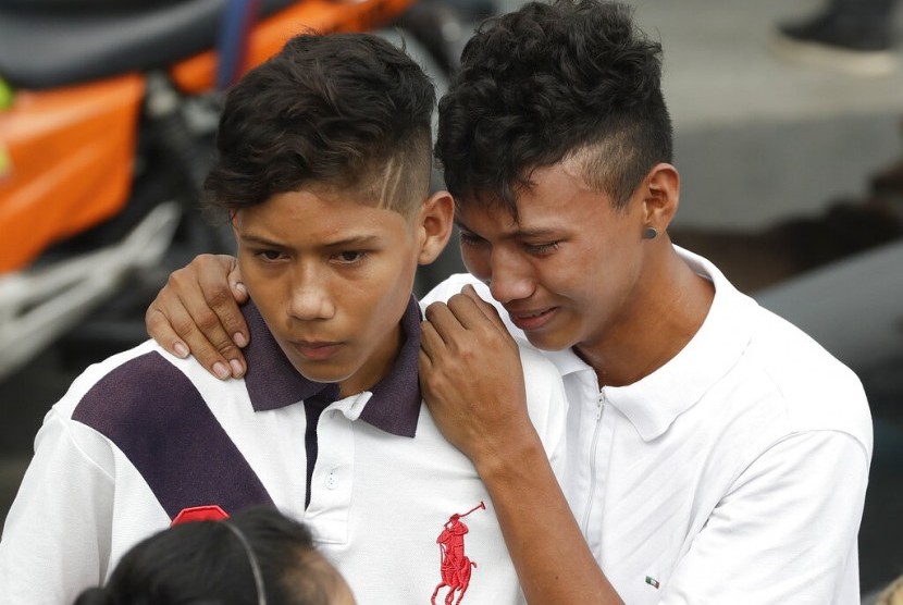 Dua orang adik menunggu jenazah kakak mereka yang tewas dalam kerusuhan penjara di Manaus, Brazil, Selasa (28/5).