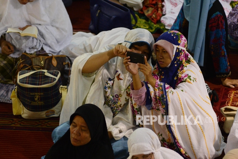 Dua orang akhwat berswafoto sebelum melaksanakan Shalat Idul Adha di Masjid Istiqlal, Jakarta, Senin (12/9). 